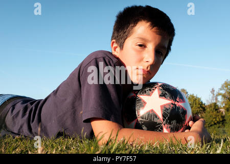 Il REGNO UNITO, 11 anni ragazzo tenere una sfera di calcio all'aperto Foto Stock