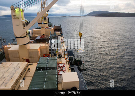 181019-N-VO150-0840 (ott. 19, 2018) marinai dalla base navale di movimentazione del carico 1 Battaglione (NCHB-1) utilizzare gru di bordo a bordo USNS 1Lt. Baldomero Lopez (T-AK 3010) per abbassare un mezzo tattico di sostituzione del veicolo (MTVR) su un Marina migliorato sistema di alleggio Causeway traghetto, azionato da anfibio battaglione di costruzione 2,, come parte del preposizionamento marittima operazioni vigore durante l'esercizio dello schermo del Nord a Bogen, Norvegia, Ottobre 19, 2018. Schermata del nord è un accordo bilaterale in materia di esercizio che coinvolge il corpo della marina degli Stati Uniti' Marine Force-Europe rotazionale (MRF-E) e il norvegese, militare ed è tenuto Foto Stock