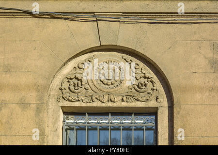 Finestra con stucchi con fregio floreale in precedenza. Decorative bassorilievo con motivo floreale sul vecchio design classico della parete edilizia Foto Stock