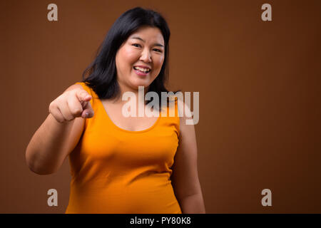 Bellissimo il sovrappeso donna asiatica sorridente e puntare il dito in telecamera Foto Stock