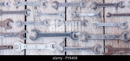 Chiave di metallo arrugginito strumenti giacente su un tavoli in legno nero. Il martello, lo scalpello, seghetto, chiave di metallo. Sporco set di utensili a mano su un pannello in legno vintage sfondo con un tools Foto Stock