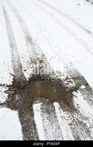 Auto tracce di pneumatico e strada fangosa coperta di neve fresca. Foto Stock