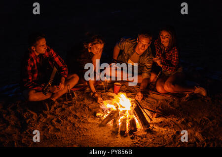 Coppie giovani hanno un picnic con falò sulla spiaggia Foto Stock