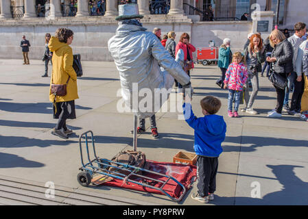 L'uomo dipinta come un argento statua umana in Trafalgar Square a Londra, Inghilterra, Regno Unito. Foto Stock