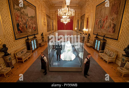 I membri del personale dal Castello di Windsor stand accanto al matrimonio abiti di il Duca e la Duchessa di Sussex, che sono andati sul display nella grande sala ricevimento al Castello di Windsor, Berkshire, come parte della mostra, un Royal Wedding: il Duca e la Duchessa di Sussex, che verrà eseguito dal 26 Ottobre al 6 gennaio 2019. Foto Stock