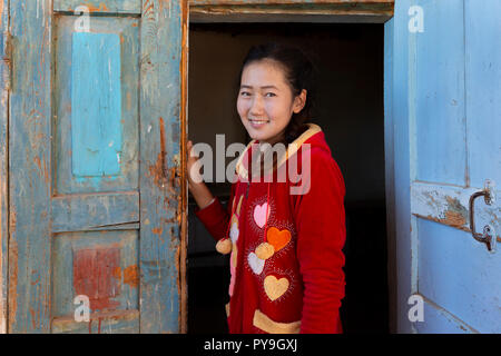 Ragazza dell'asia centrale che guarda attraverso le porte di legno, a Nukus, Uzbekistan Foto Stock