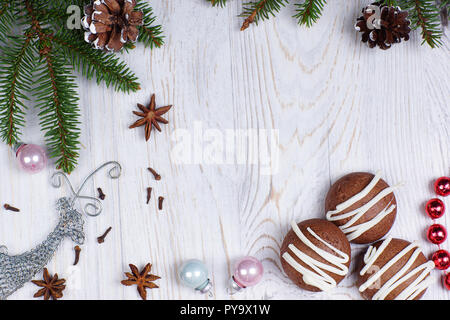 Biscotti al cioccolato, Natale i rami degli alberi e decorazioni su una luce sullo sfondo di legno. Anno nuovo concetto. Il messaggio di saluto della scheda di natale. Lay piatto. Foto Stock