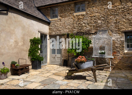 Carriola in legno con ortensie e il glicine in pentola di metallo al di fuori di casa sul cortile in pietra nel Giardino Inglese,l'Inghilterra,l'Europa Foto Stock