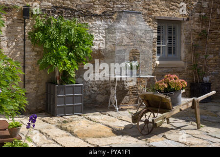 Carriola in legno con ortensie e il glicine in pentola di metallo al di fuori di casa sul cortile in pietra nel Giardino Inglese,l'Inghilterra,l'Europa Foto Stock