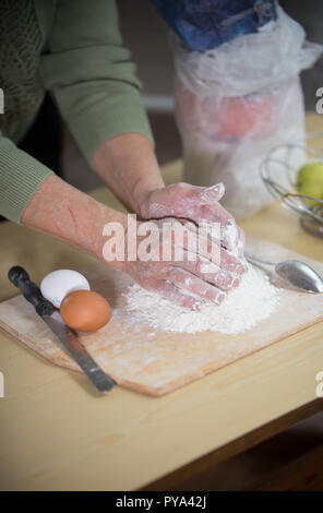 Una vecchia signora rendendo poco torte. Impastare la pasta Foto Stock