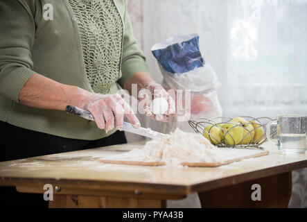 Una vecchia signora rendendo poco torte. Tenendo un uovo Foto Stock