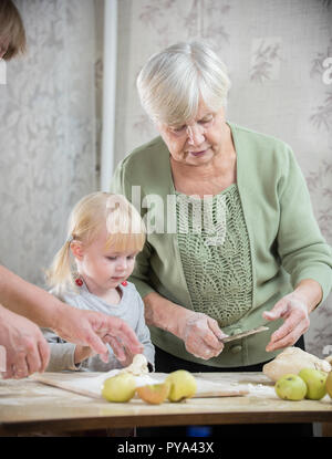 Una vecchia signora rendendo poco torte con una bambina Foto Stock