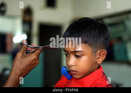 Little Boy Getting taglio di capelli da un barbiere mentre è seduto nella sedia al barbiere Foto Stock