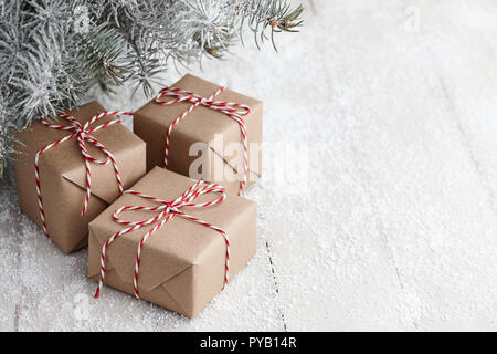 Regalo di natale scatole avvolte in carta kraft sotto snowy Abete rami, spazio di copia Foto Stock