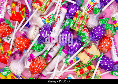 Swizzels negozio di dolci preferiti su un sfondo rosa con cuori, pop per lecca-lecca, parma violette, fizzers, bacchette, rinfrescare Foto Stock