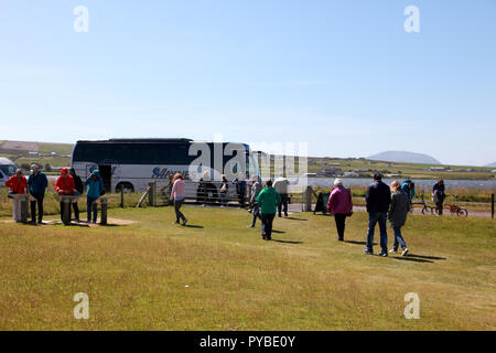 I visitatori a tornare alle loro allenatore dopo una visita a piedi di pietre di Stenness, un monumento neolitico sulle isole Orcadi, Scozia Foto Stock