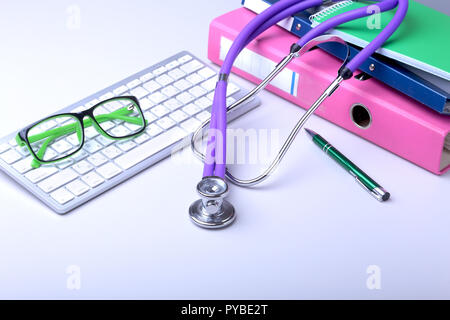 Record medici concetto con uno stetoscopio sulla pila di cartelle. Tastiera, occhiali, penna, RX prescrizione. Messa a fuoco selettiva Foto Stock