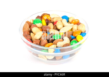 Percorso misto in recipiente di vetro. Snack mix. Mandorle, anacardi, arachidi, nocciole, uvetta e colorato di cioccolatini. Il cibo per essere presa lungo passeggiate. Foto Stock