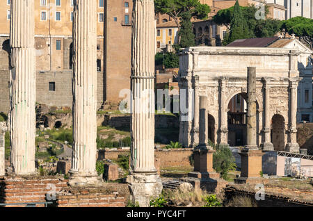 Guardando attraverso il foro romano verso l'Arco di Settimio Severo, con la columnes del Tempio dei Dioscuri in primo piano, Roma, Italia. Foto Stock