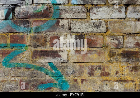 Vecchio rosso mattone parete ricoperta con resti della vecchia vernice bianca e con graffiti di una freccia blu, con spazio per il testo sul lato. Sfondo spazio di copia Foto Stock