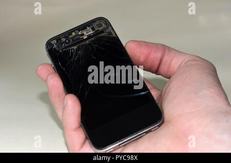 Rotto il gadget mobile in mano su uno sfondo bianco. Vetro rotto dello smartphone mrbtlnogo Foto Stock