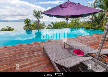 Sedie a sdraio a bordo piscina con splendida vista sul mare Foto Stock