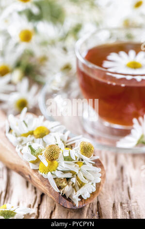 Una chiara tazza di medicinali tè camomilla su un vecchio tavolo di legno. Salute e stile di vita sano concetto. Foto Stock