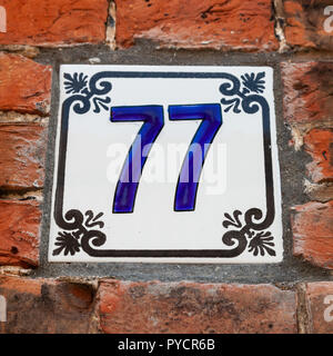 Numero di casa settantasette 77 dipinta su piastrelle di ceramica in blu e nero con Fleur de Lis pattern da Svezia e Belgio Foto Stock