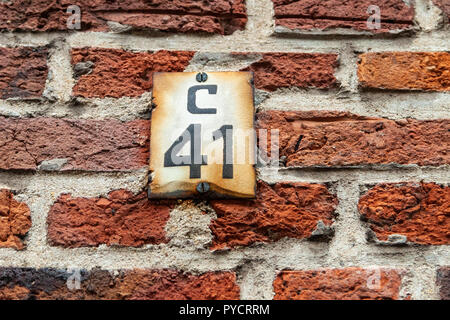 Numero di casa quaranta-one C 41C verniciato nero su arrugginita cercando e danni di pietra bianca avvitata a mattoni in Svezia Foto Stock