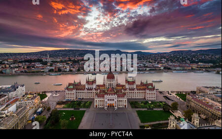 Budapest, Ungheria - Aerial vista panoramica del Parlamento di Ungheria al tramonto con belle drammatico nuvole viola e le imbarcazioni turistiche sul fiume Foto Stock