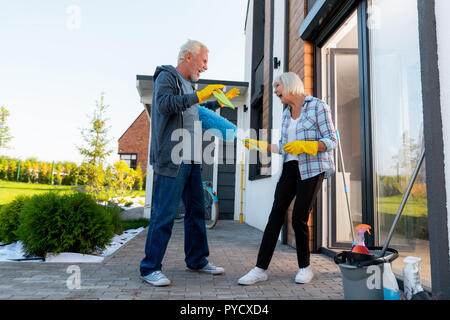 Moderno ridere la nonna e nonno avente fun territorio di pulizia Foto Stock