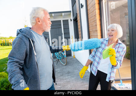 Uomo Barbuto divertendosi con la sua affascinante moglie mentre facendo pulizia Foto Stock