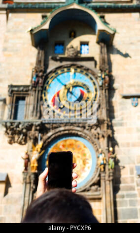 Primo piano di un giovane uomo caucasico, visto da dietro, scattare una foto del celebre Medieval orologio astronomico di Praga, nella Repubblica Ceca, con il suo Foto Stock