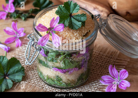 Preparazione di uno sciroppo in casa contro la tosse da selvatici comuni fiori malva e zucchero di canna Foto Stock