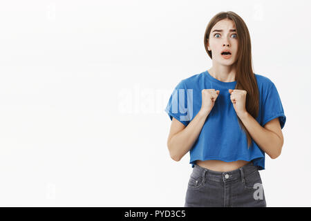 Donna di essere preoccupato per l'amico mettersi in pericolo permanente senza fiato storditi e intensi stringendo i pugni nervosamente vicino al petto di aprire bocca, sensazione di empatia e di ansia su sfondo grigio Foto Stock