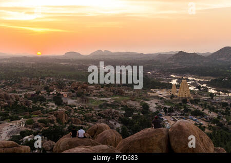 Scenic tramonto sul paesaggio punteggiato di giganteschi massi e rovine accanto al fiume Tungabhadra come visto da Matanga Hill Top, Hampi, Karnataka, India. Foto Stock