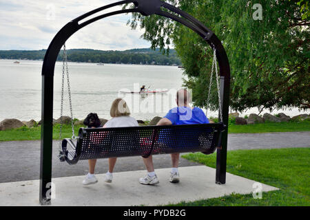 Coppia seduta sul banco di swing in Kershaw parco affacciato sul lago Canandaigua, NY, STATI UNITI D'AMERICA Foto Stock