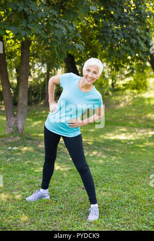 Ritratto di donna senior facendo esercizi streching nel parco Foto Stock