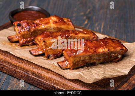 Grigliata di costolette di maiale in salsa barbecue sul piatto di legno Foto Stock