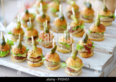 Un delizioso boccone mini hamburger servita su una parte o un ricevimento di matrimonio. Le piastre con fantasia assortiti di finger food snack su un evento parte o la cena. Foto Stock