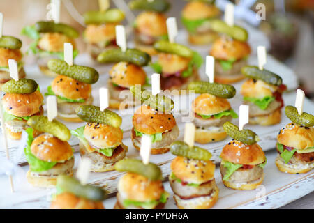 Un delizioso boccone mini hamburger servita su una parte o un ricevimento di matrimonio. Le piastre con fantasia assortiti di finger food snack su un evento parte o la cena. Foto Stock