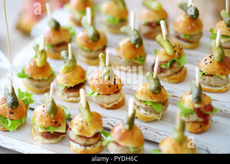 Un delizioso boccone mini hamburger servita su una parte o un ricevimento di matrimonio. Le piastre con fantasia assortiti di finger food snack su un evento parte o la cena. Foto Stock