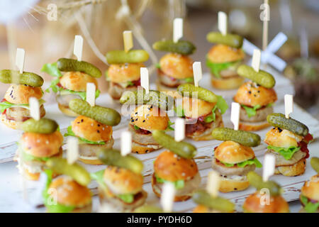 Un delizioso boccone mini hamburger servita su una parte o un ricevimento di matrimonio. Le piastre con fantasia assortiti di finger food snack su un evento parte o la cena. Foto Stock