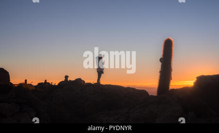 Vista sul tramonto sull isola incahuasi dal lago di sale di Uyuni in Bolivia, ragazza silhouette Foto Stock