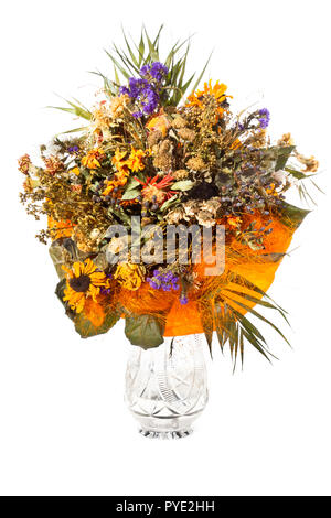 Un grosso mazzo di fiori secchi di varie specie di fiori in un vaso di cristallo su uno sfondo bianco. Foto Stock