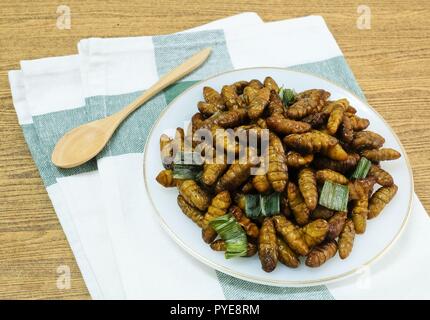 La cucina e il cibo tailandese tradizionale profondo fritto marinato vermi di noce di cocco con erbe su un piatto bianco. Uno dei più popolari street food in Thailandia. Foto Stock