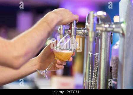 Barman nel pub versando una lager la birra in un bicchiere, shallow dof, il fuoco selettivo. Foto Stock