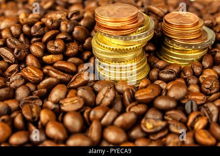 I chicchi di caffè e denaro. Il commercio equo e solidale. Vendita di caffè. Commercio di prodotti. Freschi i chicchi di caffè. Colonna di monete metalliche in euro Foto Stock