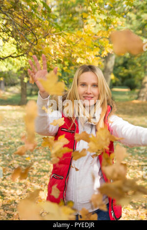 Donna allegra giocando con colorati cadono le foglie in autunno park Foto Stock