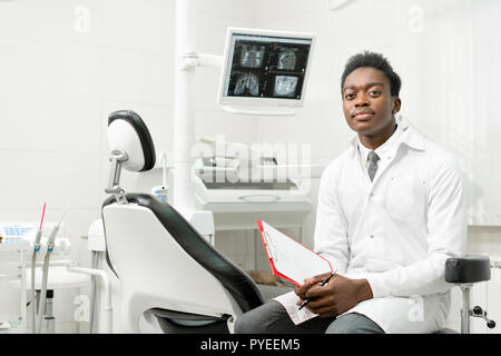 I giovani africani maschio americano medico dentista in studio dentistico. Medicina, salute stomatologia concetto. Guardando nella telecamera Foto Stock